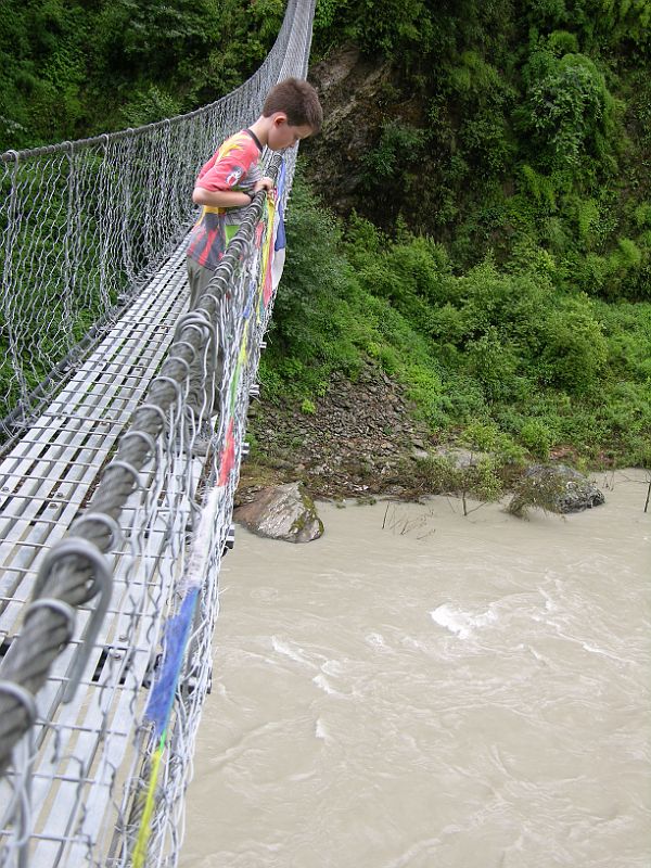 04 Peter Ryan On Bridge Over Bhote Kosi Just Before Kodari While we waited for the porters to carry our stuff across the landslide, Peter Ryan walked part way across a bridge over the Bhote Kosi river.